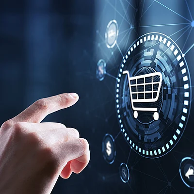 Hand bedient digitales Einkaufsinterface mit Warenkorb-Symbol und vernetzten Icons.