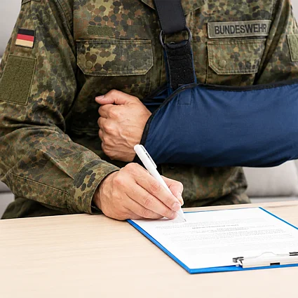Verletzter Soldat unterzeichnet Dokument als Symbol für Absicherung bei Dienstunfähigkeit und Risikolebensversicherung.