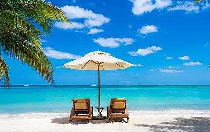 Sonnenliegen unter Palmen am tropischen Strand – Symbol für Reisen, Erholung und Urlaub.