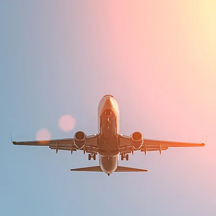 Flugzeug im Flug vor farbigem Himmel als Symbol für Reisen, Urlaub und weltweite Mobilität.